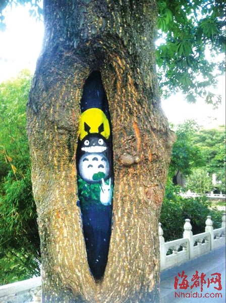 “樹洞畫”萌萌噠　兩大學(xué)生在校園行道樹上繪畫